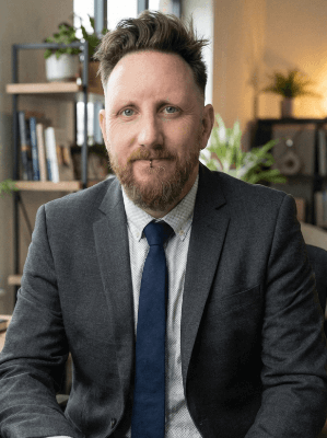 Alex Harvey, AI consultant in Canterbury, standing in front of a modern building